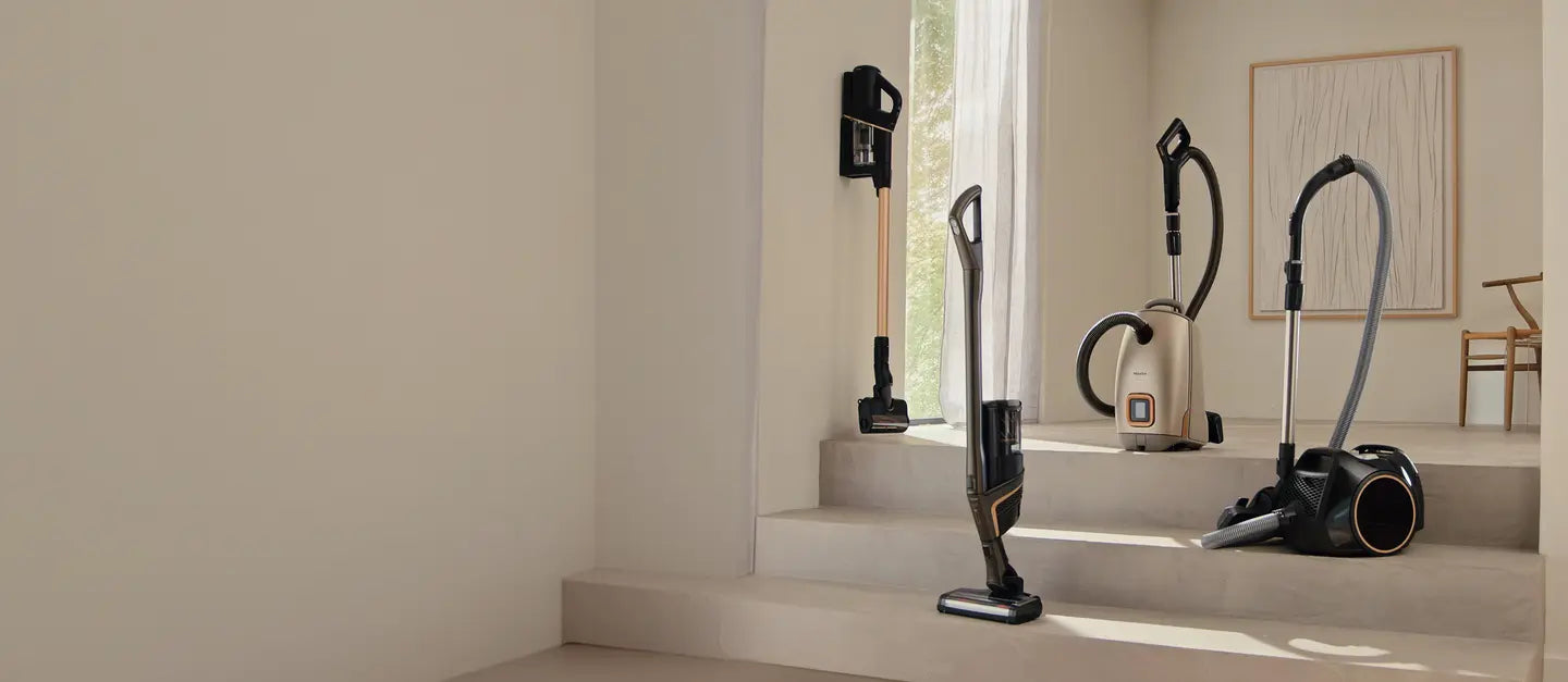 Miele stick, canister and bagged vacuums on a set of stone steps